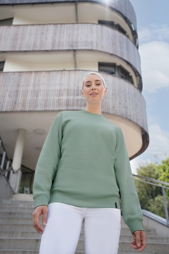 Zdjęcie aranżowane kobiety w bluzie dresowej zakładanej przez głowę, bluza w kolorze zieleni pistacjowej.